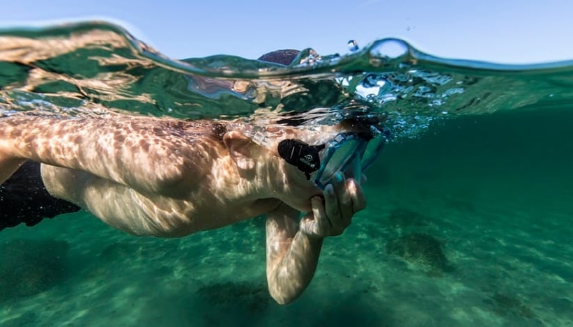 Bading er en populær friluftsaktivitet i Norge. Bildet er tatt under vann og viser et barn som snorkler.